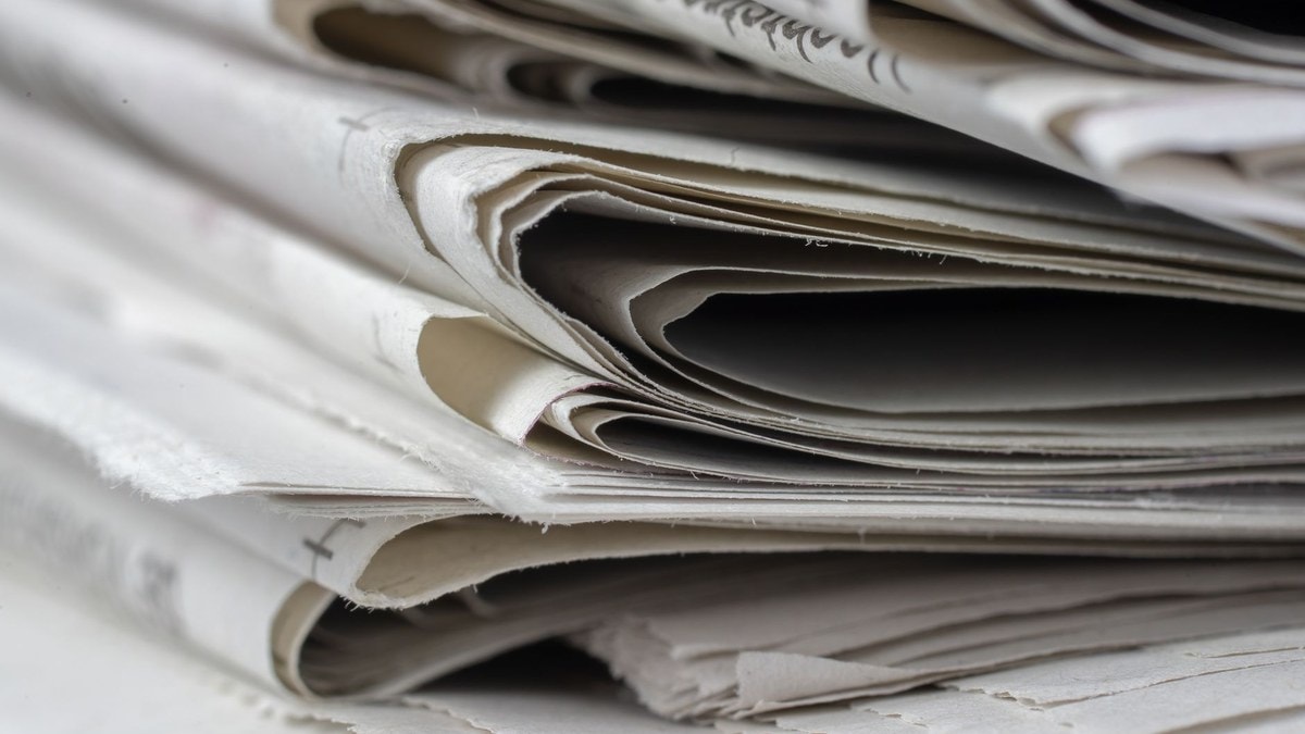 Pile de journaux illustrant la préparation d'un dossier de presse